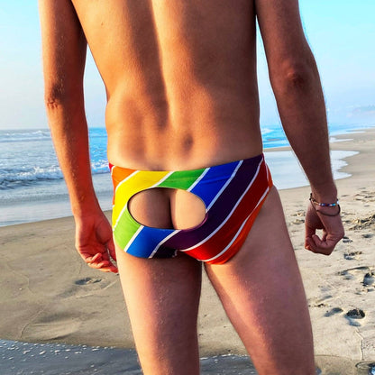 Model wearing rainbow stripe swim briefs on beach