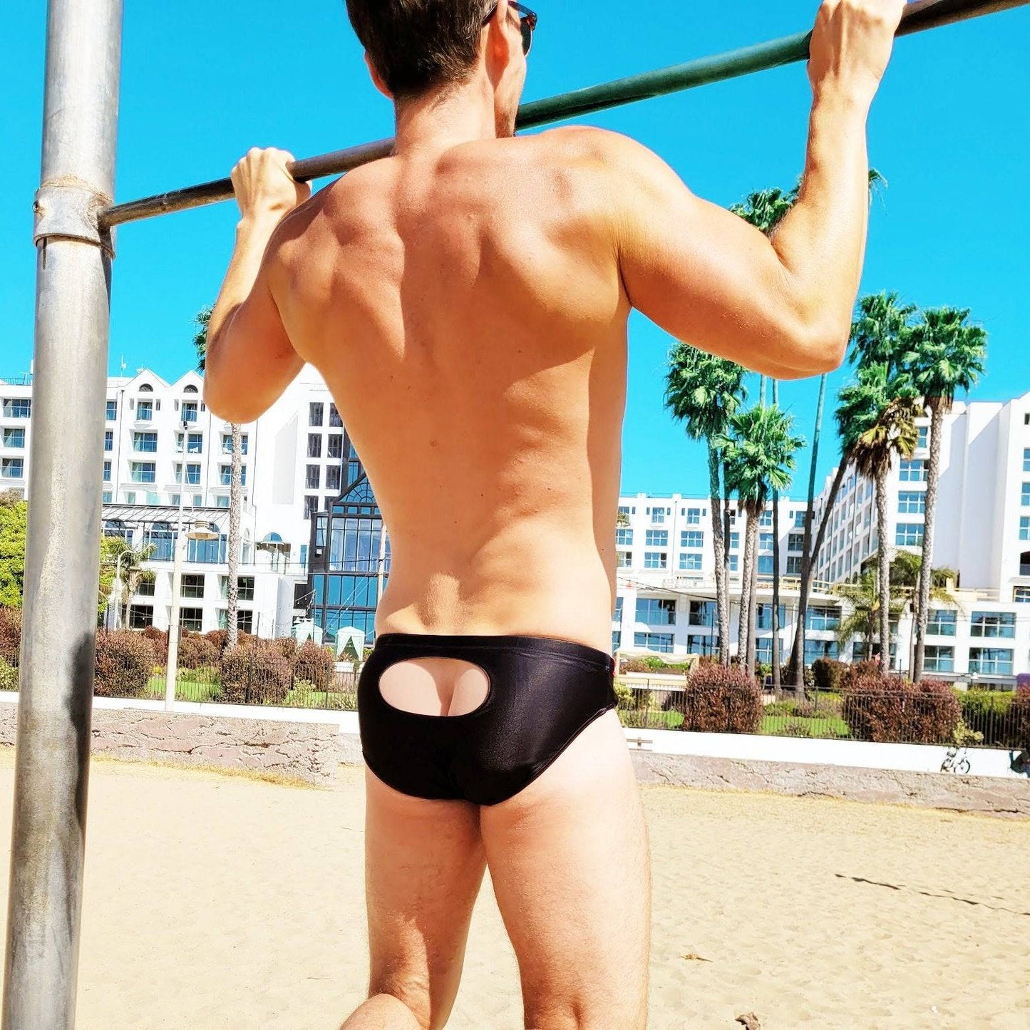 Man wearing Black Open Window swim briefs on beach