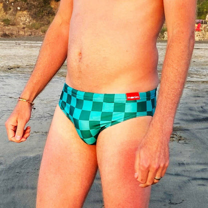 Front view of blue checkerboard swim briefs on beach